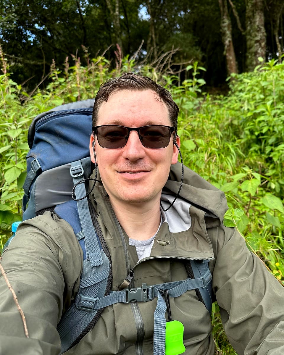 Chris Elkins hiking with a backpack in a forest